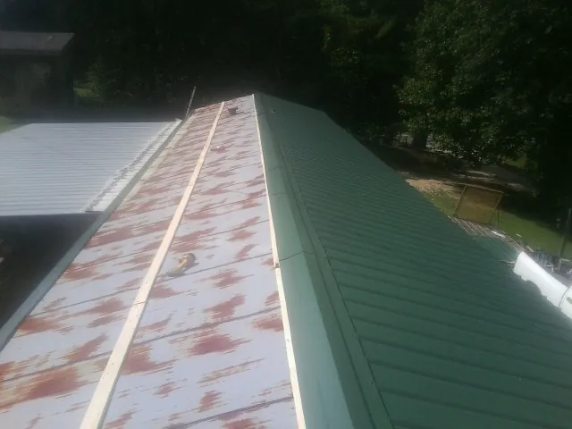Old rusted panels beside newly installed green metal roofing — Wind Damage Roof Repair by Roofing Brothers in Richland Center