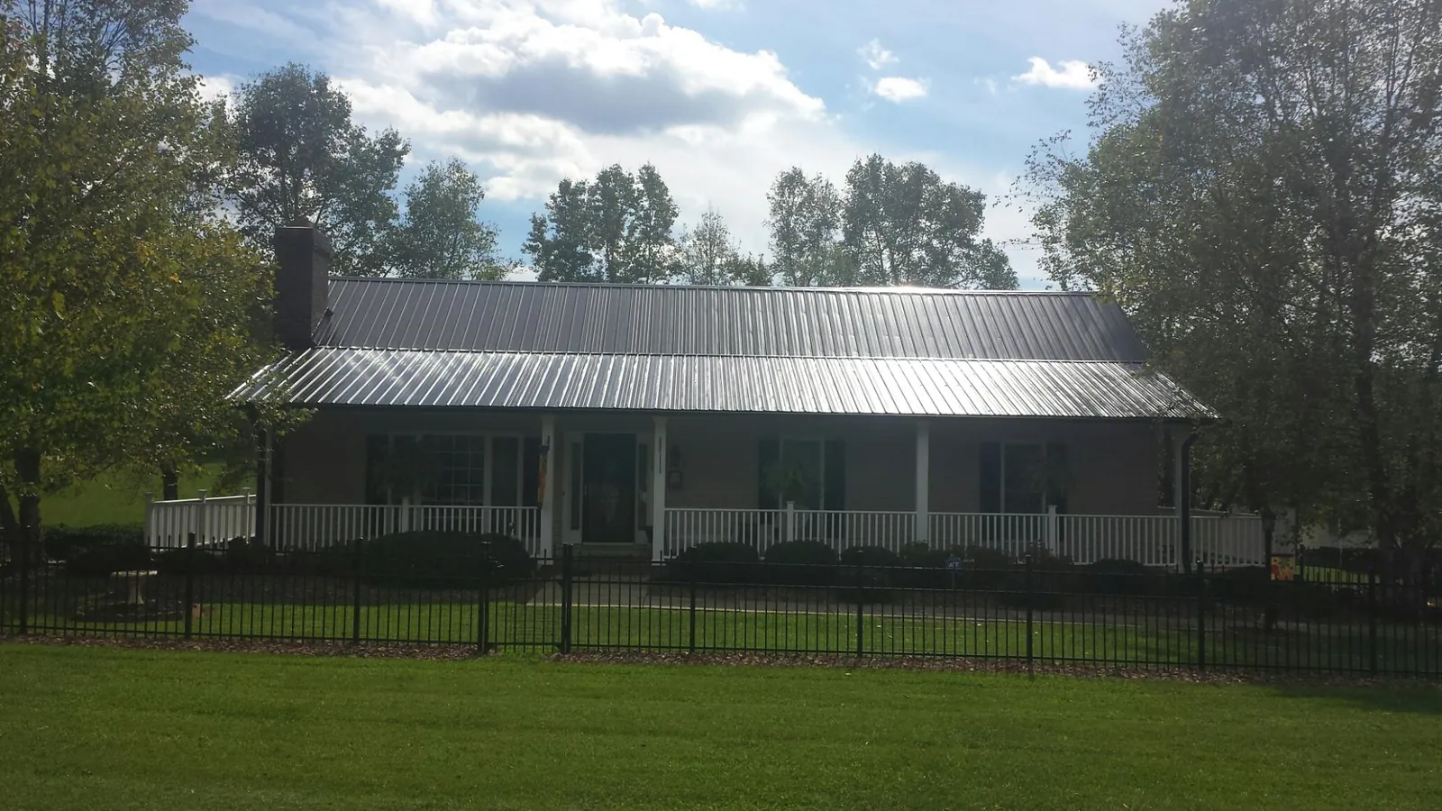 Gray metal roof on a brick ranch with a full width front porch — Gutter Guard Installation work by our crew in Richland Center
