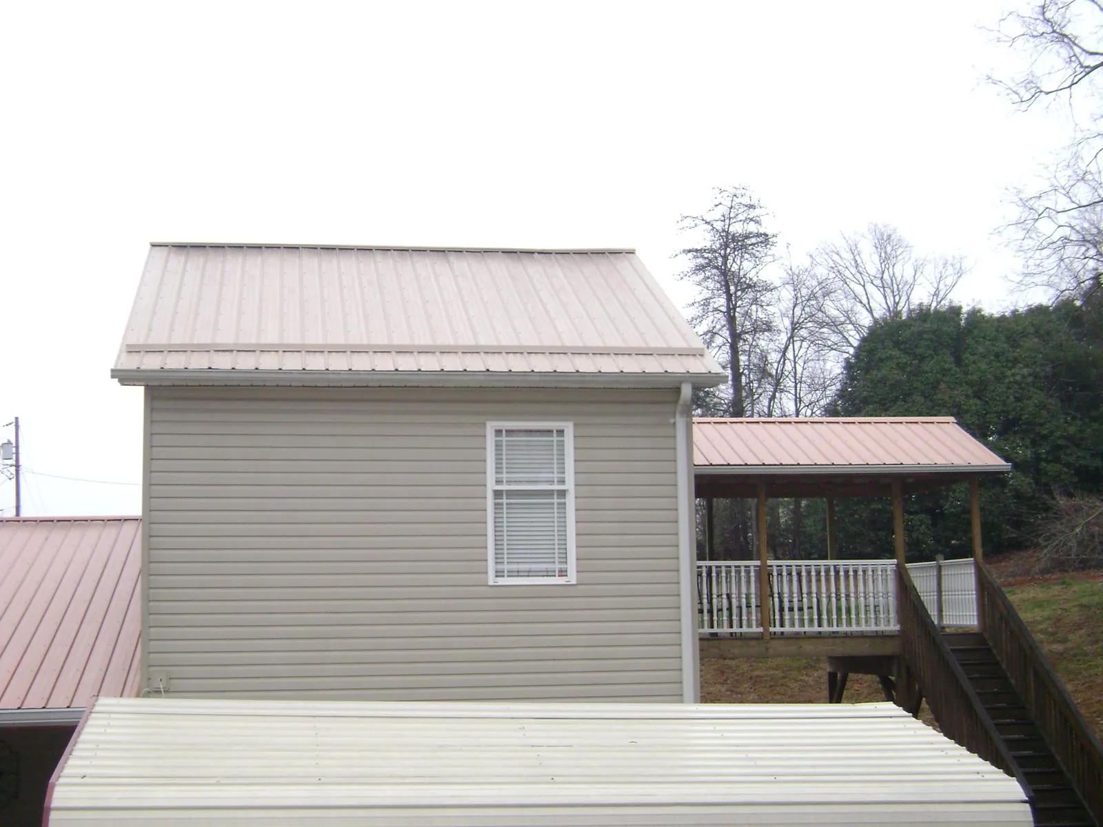 Tan metal roofs on a two story addition and attached porch, from a Roof Replacement job in Richland Center