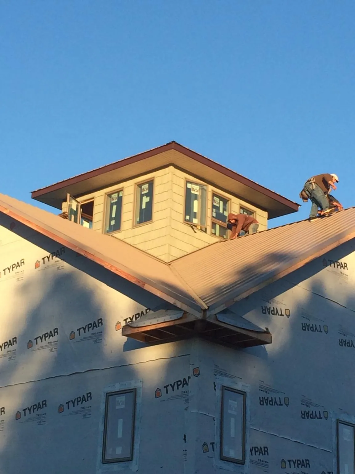 Roofers working around a rooftop cupola on a new metal roof at sunset — Roof Waterproofing in Richland Center by Roofing Brothers